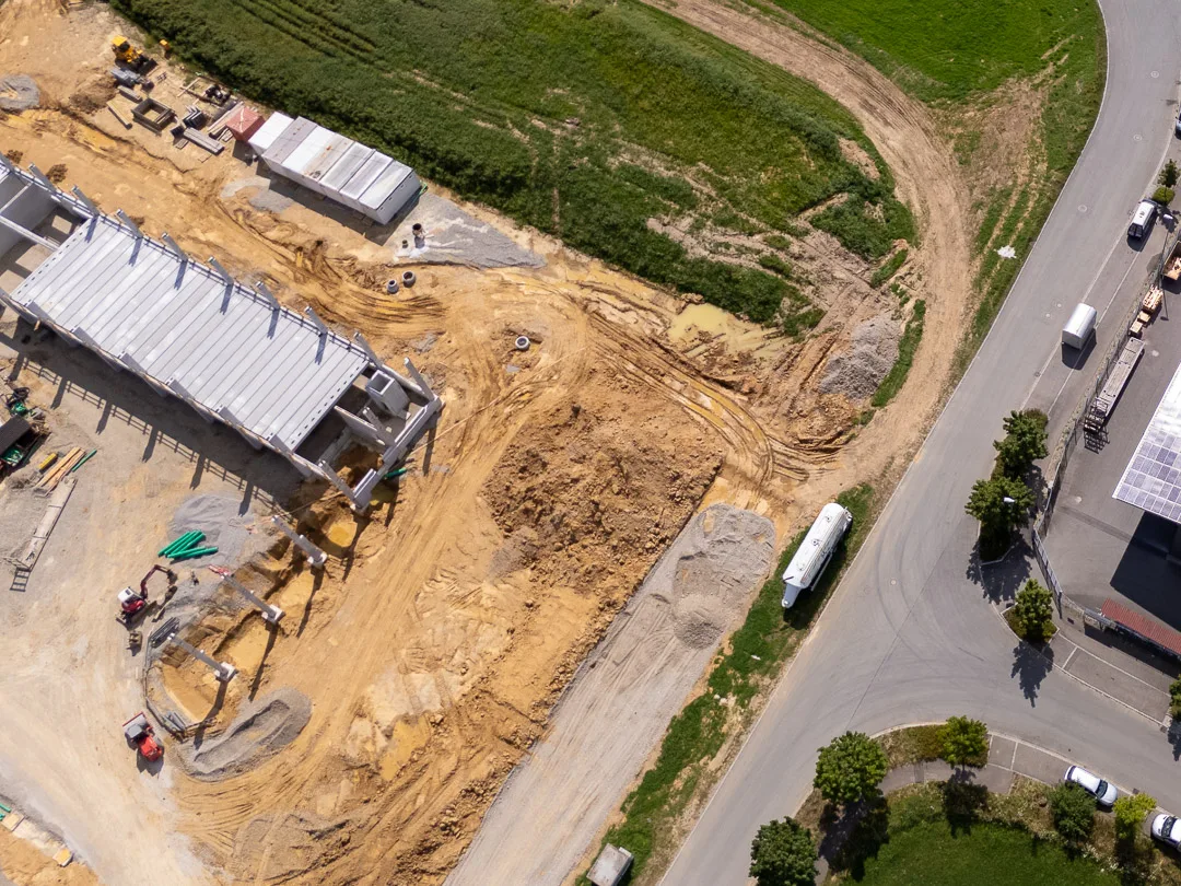 Senkrechte Luftaufnahme einer Baustelle mit Baugrube, Erdaushub und Fundamenten