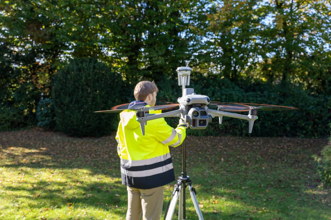 Fernpilot startet eine Vermessungsdrohne, daneben die RTK-Basisstation auf einem Stativ